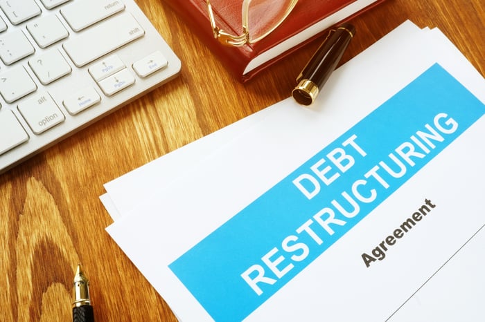 A written debt restructuring agreement lying on a wooden desk