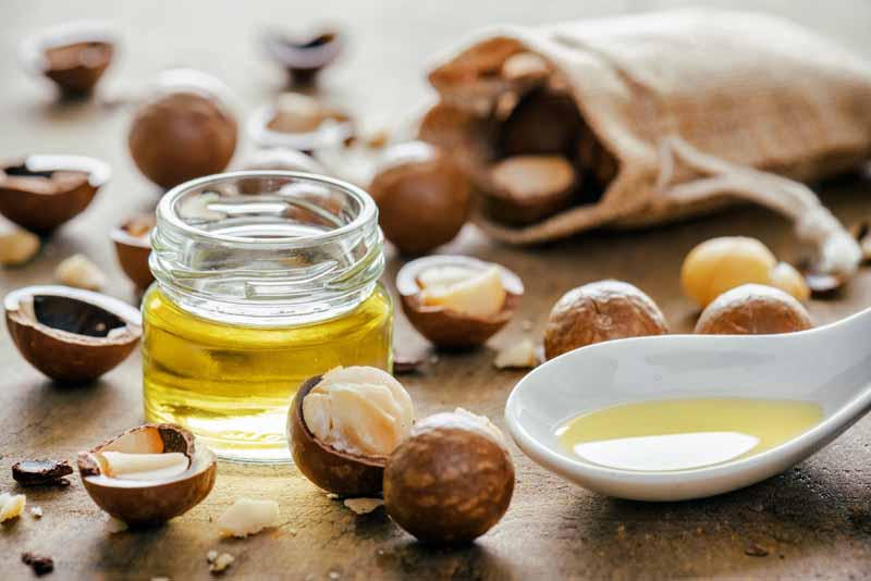 Macadamia nuts and oil on a wooden table top.