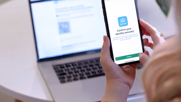 A person holding a mobile phone using the GOV.UK One Login app