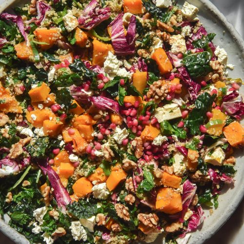 An aerial image of a plate of roast pumpkin salad on a white marble table