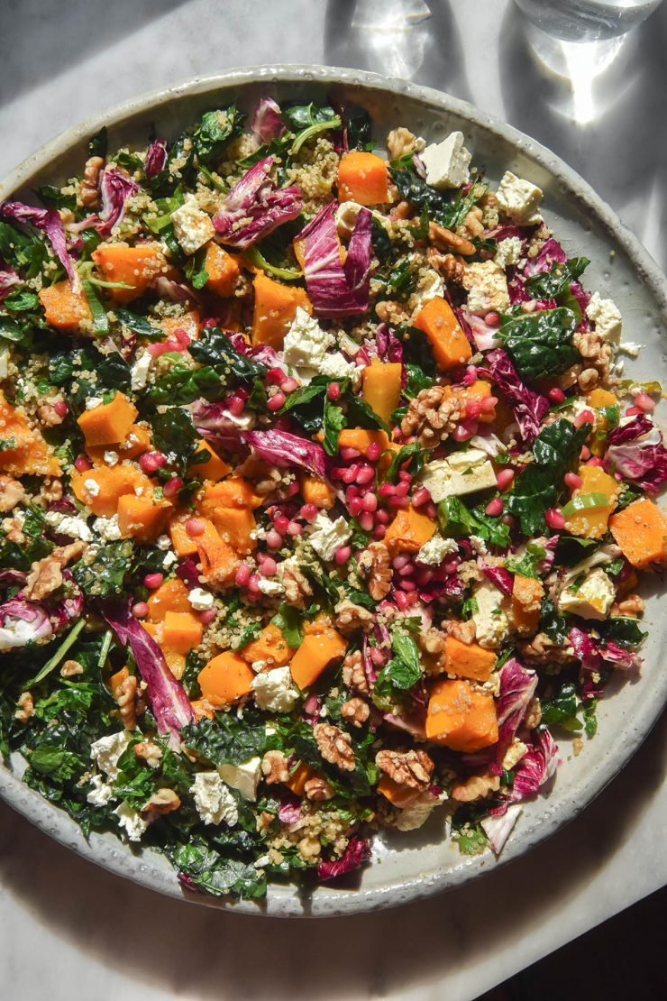 An aerial image of a plate of roast pumpkin salad on a white marble table