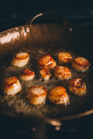 Scallops in a frying pan on a stove.