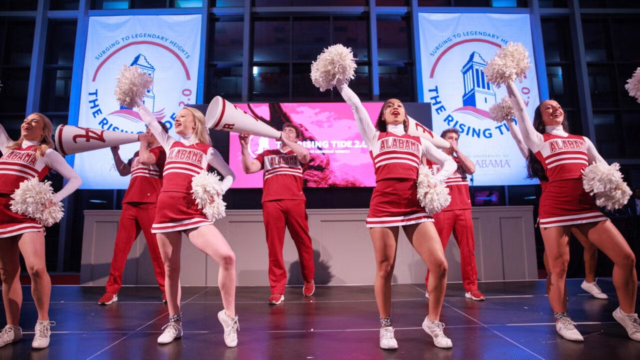 male and female cheerleaders lead a cheer during an indoor event