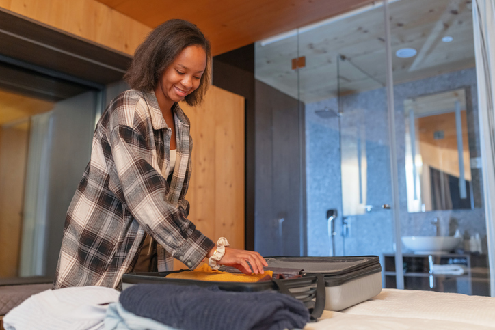 Woman packing her suitcase in a hotel room, returning home after a business trip