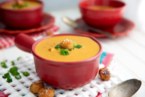 Beer Cheese Soup in a maroon colored ceramic bowl with handle