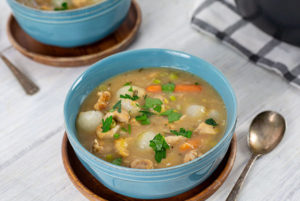 ACV Chicken Stew in a blue bowl on top of a wooden plate