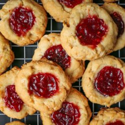 overhead shot of raspberry thumbprint cookies on wire rack.