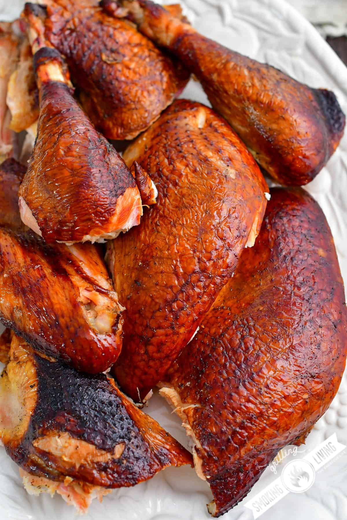 top view of smoked turkey pieces laying down on a white plate