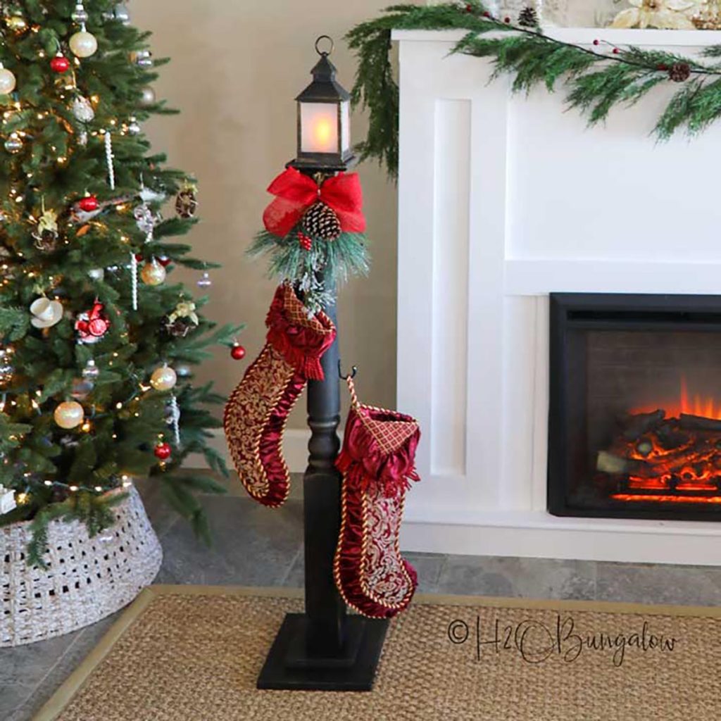 completed DIY stocking holder stand with stockings in front of the Christmas tree and fireplace