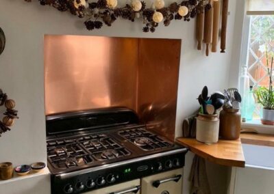 rustic kitchen with orange copper splashback in alcove