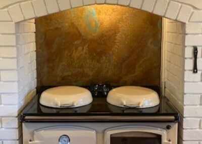 patina copper splashback behind white AGA