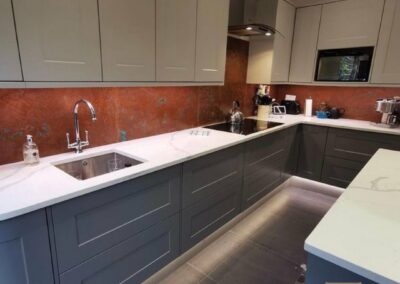 large kitchen finished with glossy aged copper splashback