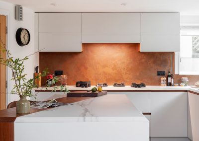 aged copper backsplash with plug cutouts behind kitchen hob