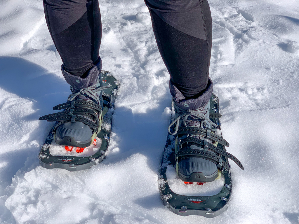 Close up of a a person wearing insulated hiking boots with snowshoes. The best boots for snowshoeing