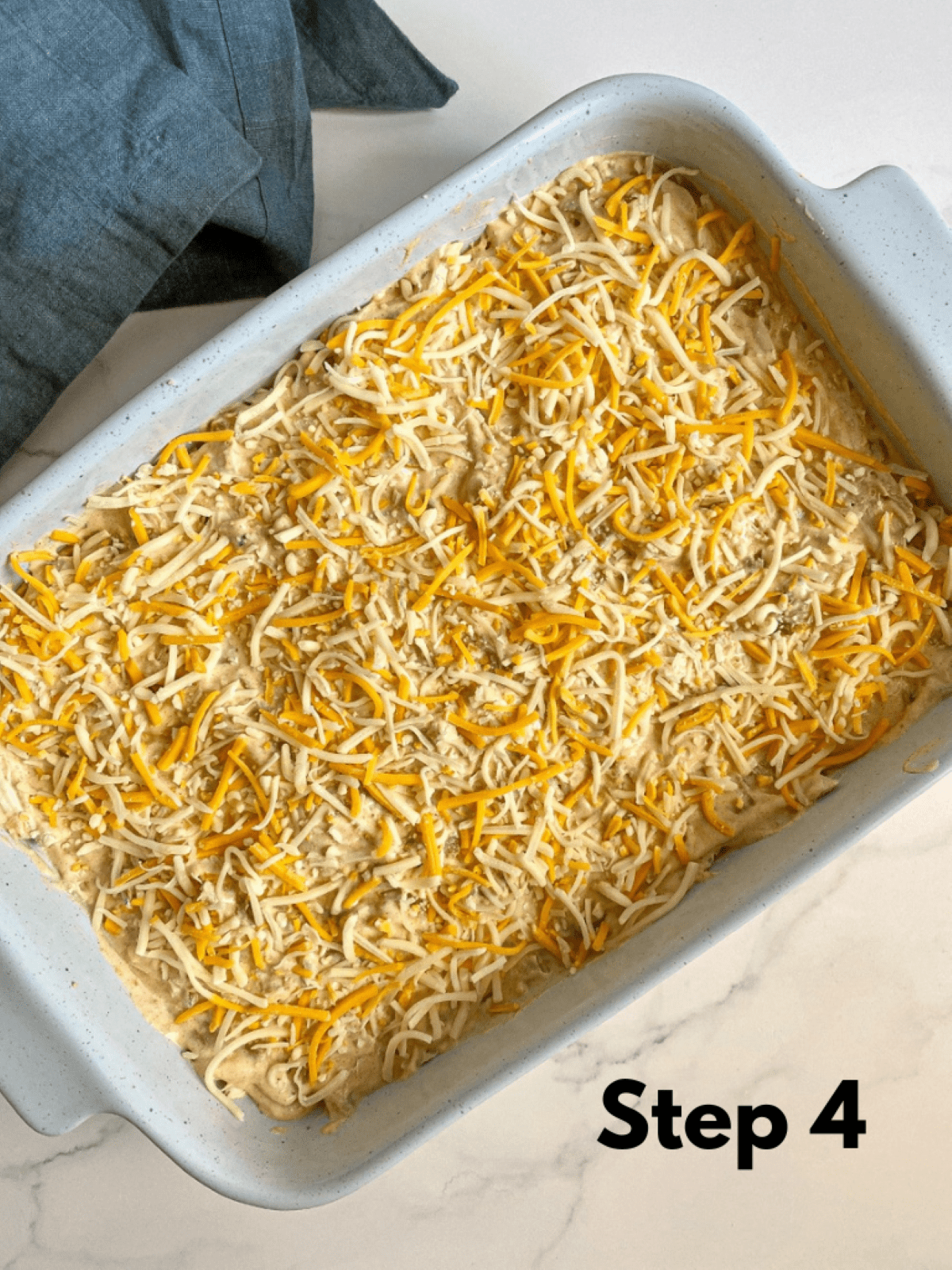 Shredded cheese layered on top of corn tortillas, chicken, and sour cream sauce. The final and fourth layer in the casserole dish.