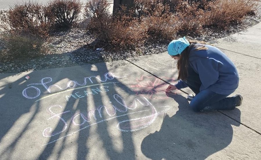 Junior Caitlin Leiker completes a chalk drawing on someone's driveway. Leiker drove around leaving positive chalk messages for different friends and acquaintances as well as leaving drawings in front of the Hays Medical Center. "It's been a pretty difficult during this time, especially for people who live alone," Leiker said. "I figured the least I could was try to spread some positivity."