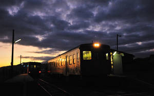 A Chugging Train Heads Into The Orange Sunset Wallpaper