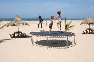 Kids Jumping On A Trampoline Near The Beach Wallpaper