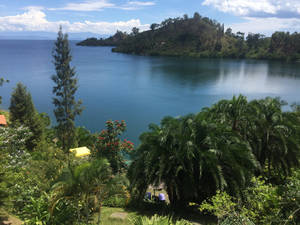 The Breathtaking Landscape Of Burundi: A Serene Sea Surrounded By Lush Green Hills Wallpaper