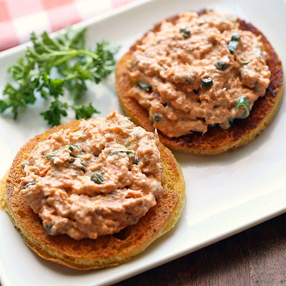 Salmon salad is served on bread slices with parsley for garnish.