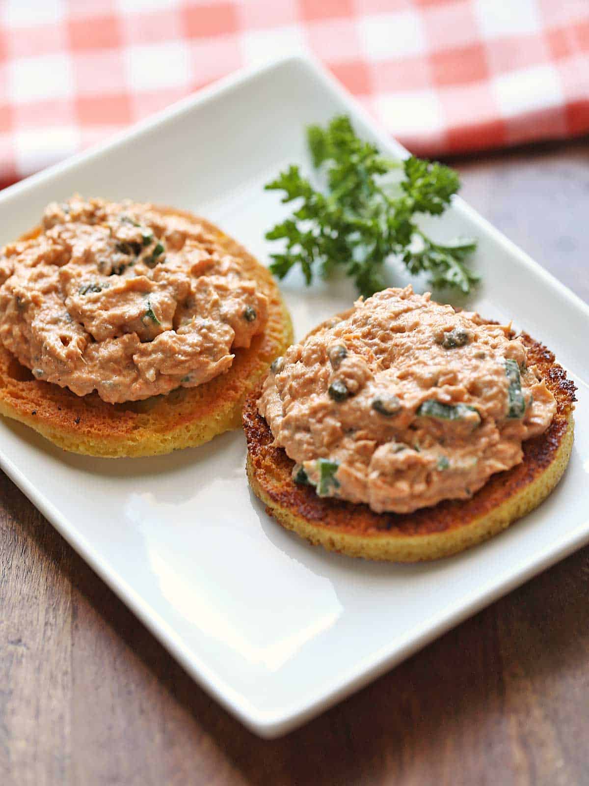 Salmon salad is served on toast, with a napkin in the background. 