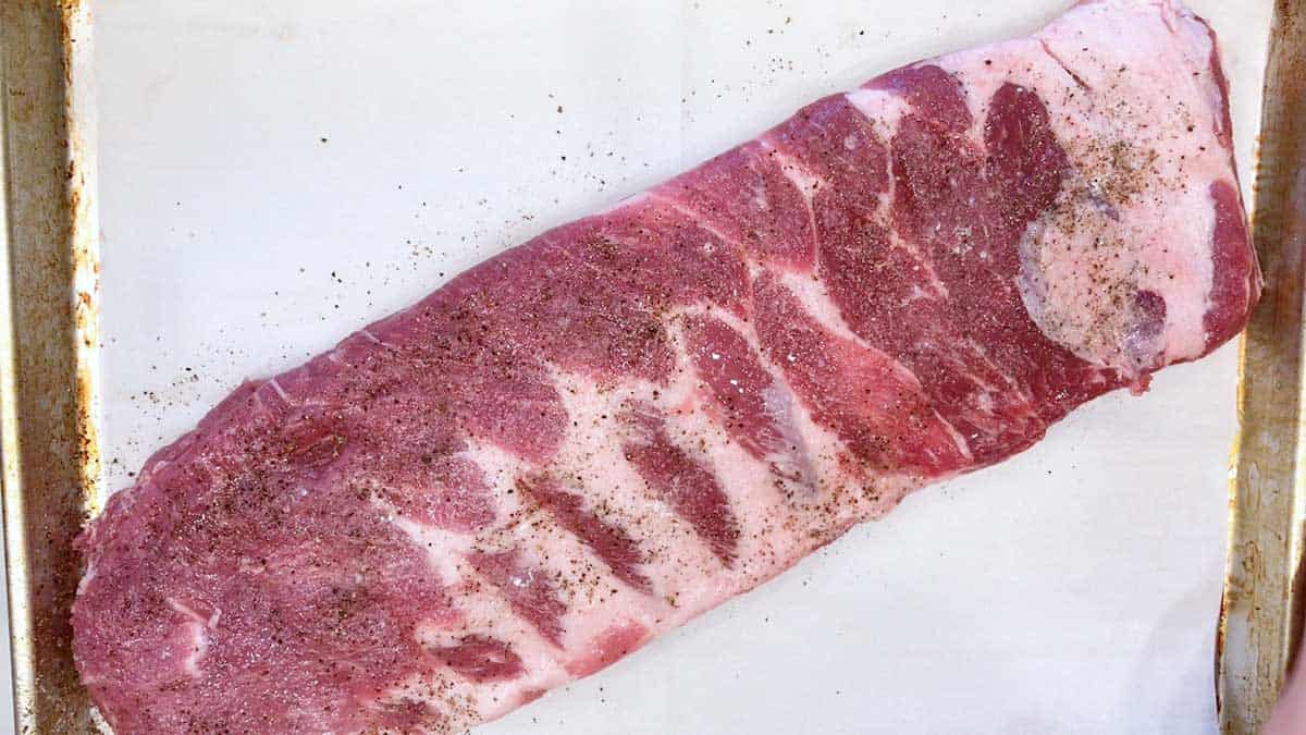 Raw spareribs on a baking sheet. 