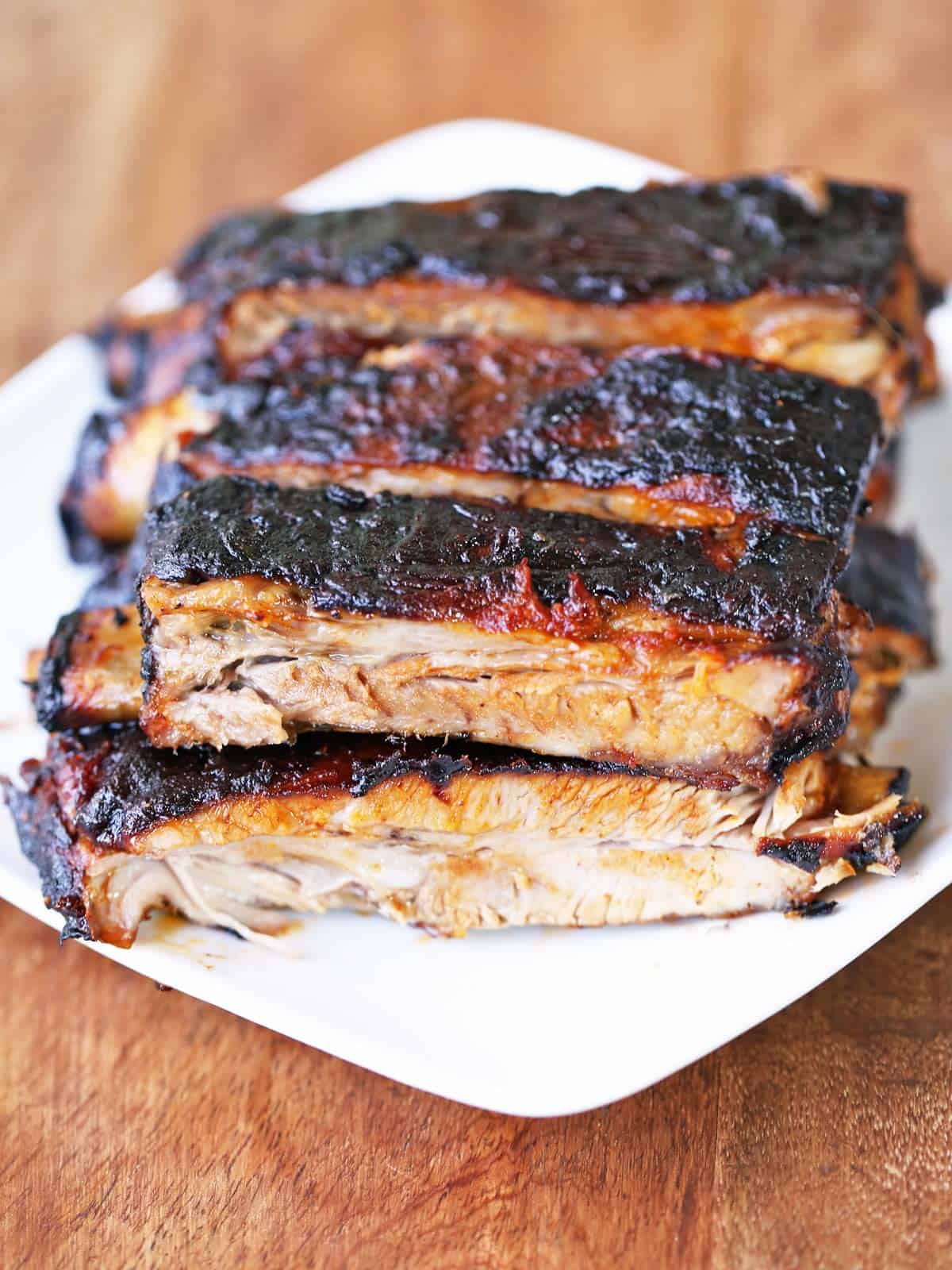 Oven baked ribs are served on a white plate.