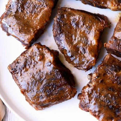 Boneless short ribs are served on a white plate.