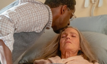 A man (Sterling K. Brown as Randall) kissing the forehead of a woman (Mandy Moore as Rebecca) who's in bed.