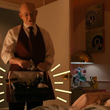 A man standing in a bedroom holding a gift basket.