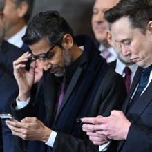 Google CEO Sundar Pichai and Tesla CEO Elon Musk look at their phones while Amazon's Jeff Bezos looks away.