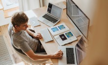 Man sat at desk with papers and laptop