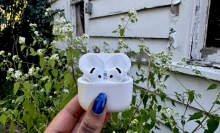 AirPods 4 in front of a tattered white shed