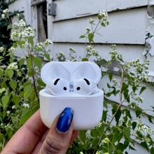 AirPods 4 in front of a tattered white shed