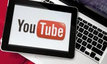 Youtube logo on iPad screen on top of the Apple Macbook Pro. 