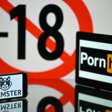 screens displaying an age restriction warning sign and the logos of the pornographic sites Pornhub (R) and Xhamster (L)