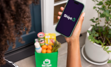 Person holding a smartphone with the Shipt logo 