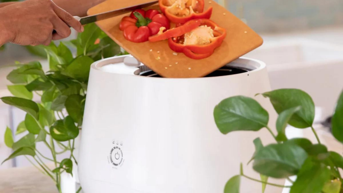 Person's hands scraping vegetables into Lomi composter