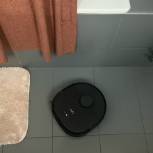 Shark robot vacuum cleaning tile floor near bathtub