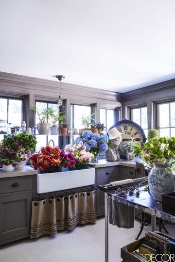 room with sink full of flowers, an oversized vintage clock, big windows, and a gray color palette