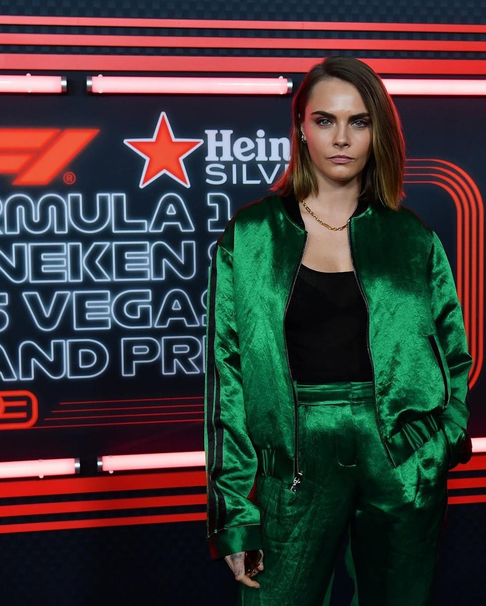 a person wearing a green outfit stands in front of a formula 1 promotional backdrop