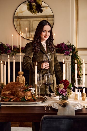 A festive dining table set for a celebration with a woman holding a wine glass