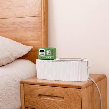 a bedside table with a retrostyle green speaker and a charging smartphone