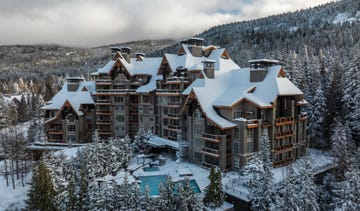 Mountain resort complex surrounded by snow-covered trees.