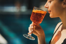 woman drinking aperol spritz by the pool