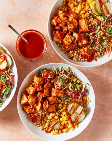 bbq chicken in a grain bowl with corn, pickles, and slaw