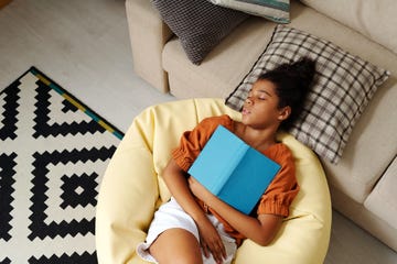 young girl sleeping on bean bag with book