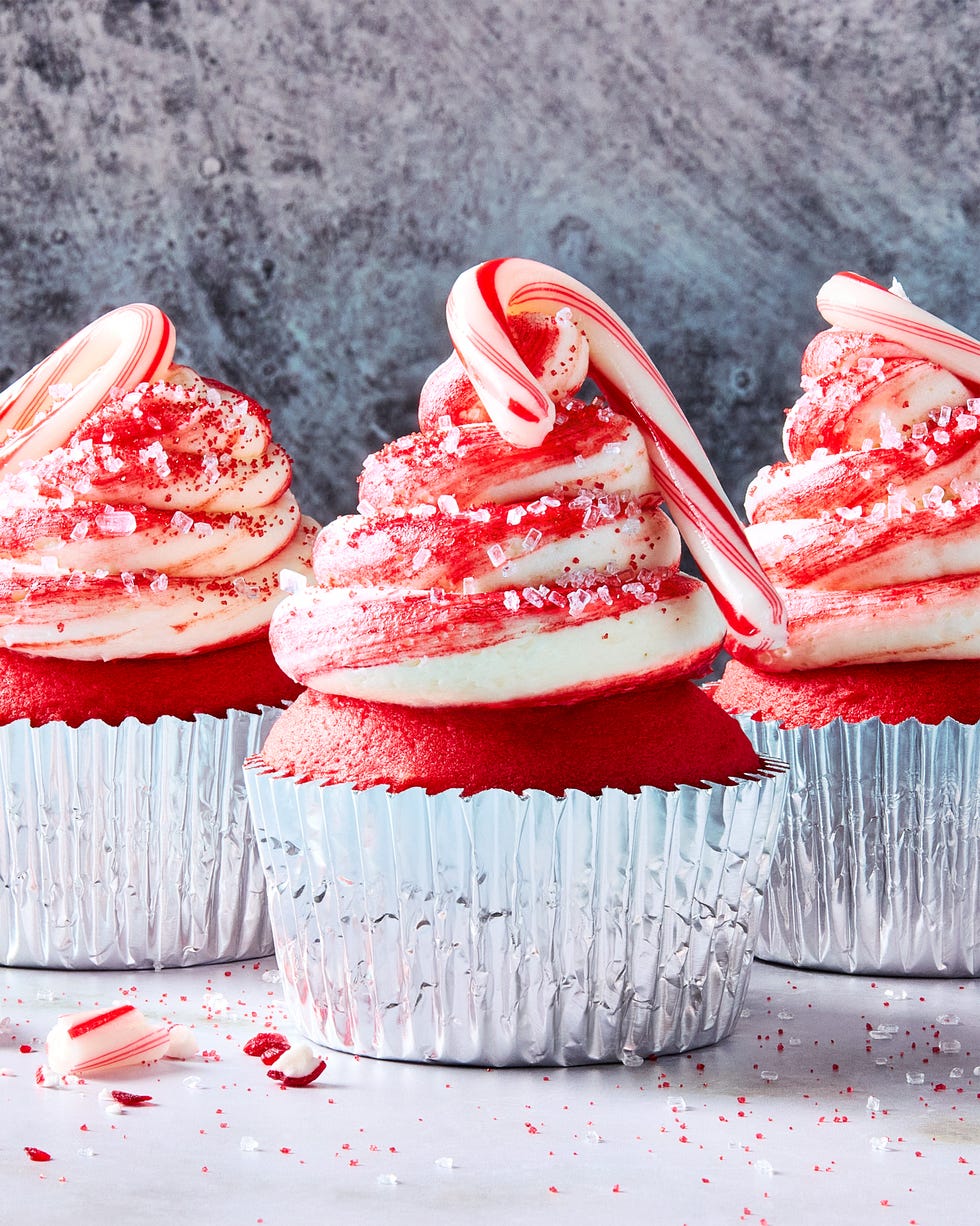 red cupcakes with icing topped with mini candy canes