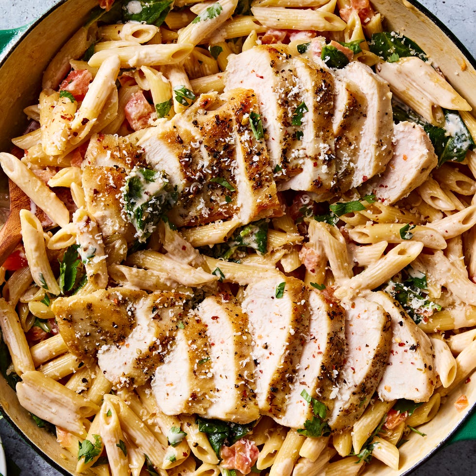 pasta in a pot topped with chicken slices and herbs