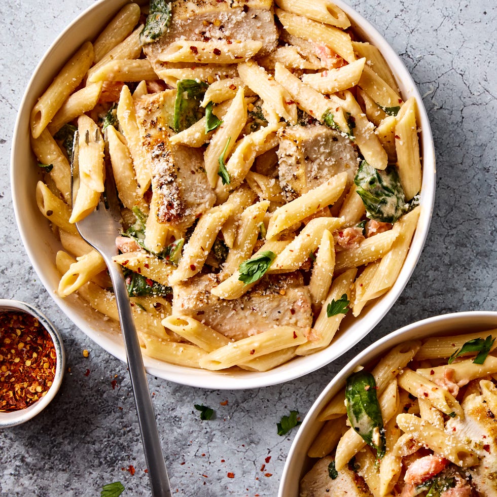 pasta in a pot topped with chicken slices and herbs